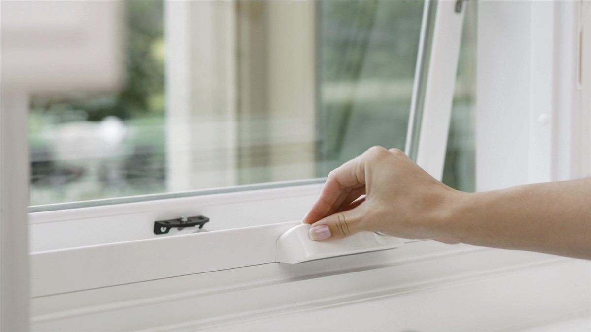 hand opening a window with white frames