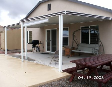 Aluminum patio cover attached to a house over a backyard seating area