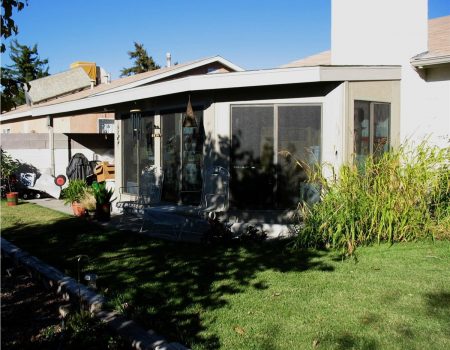 Home exterior with sunroom addition and landscaped backyard at dusk