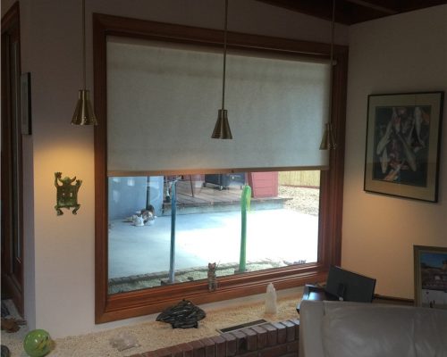 Wood-framed window with pull-down shade in a Tijeras home