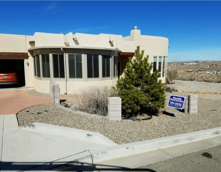 Curved sunroom addition on a stucco home with a Sandia Sunrooms yard sign